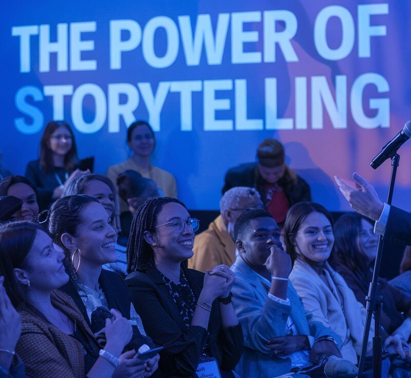 a photo of a diverse audience reacting to a speaker on stage